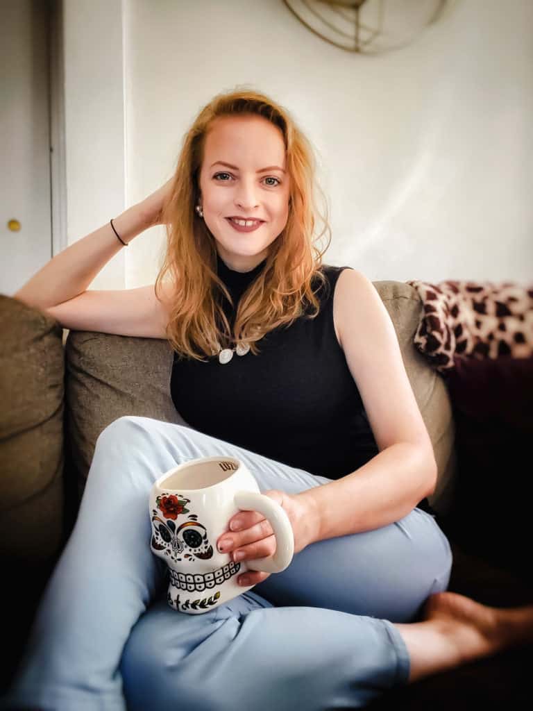 April, the creator of 12 Kitchens at home on the couch with a cup of coffee