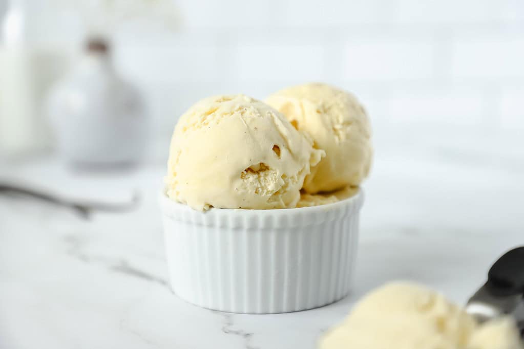 A close up shot of several scoops of smoked vanilla ice cream in a small white ramekin