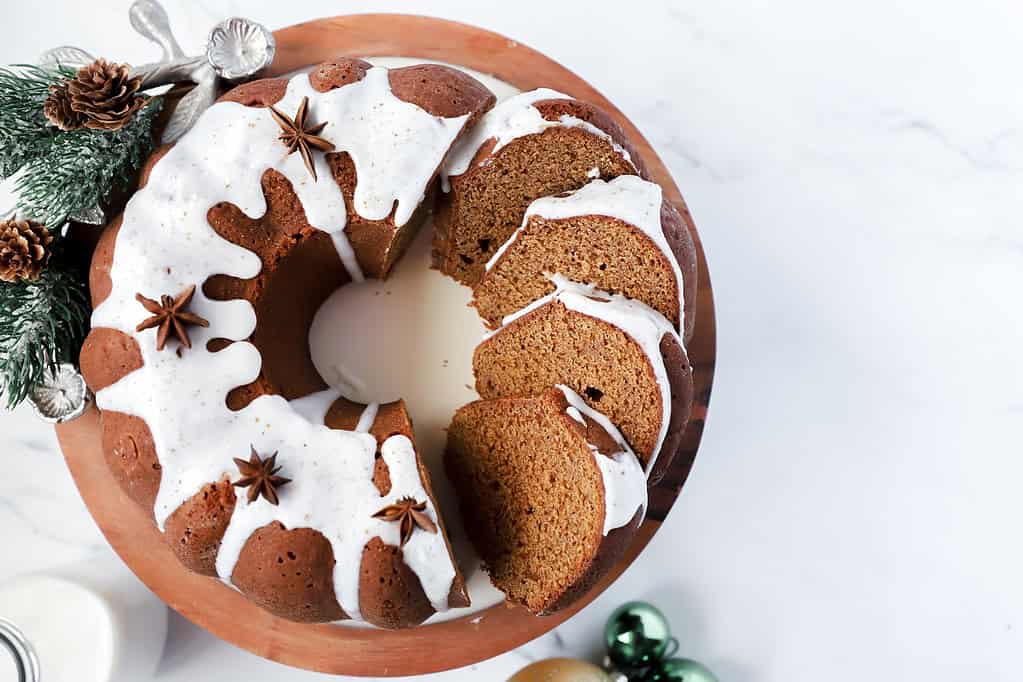 Looking down at the gingerbread bundt cake on a cake stand with several pieces laying on its side like dominoes